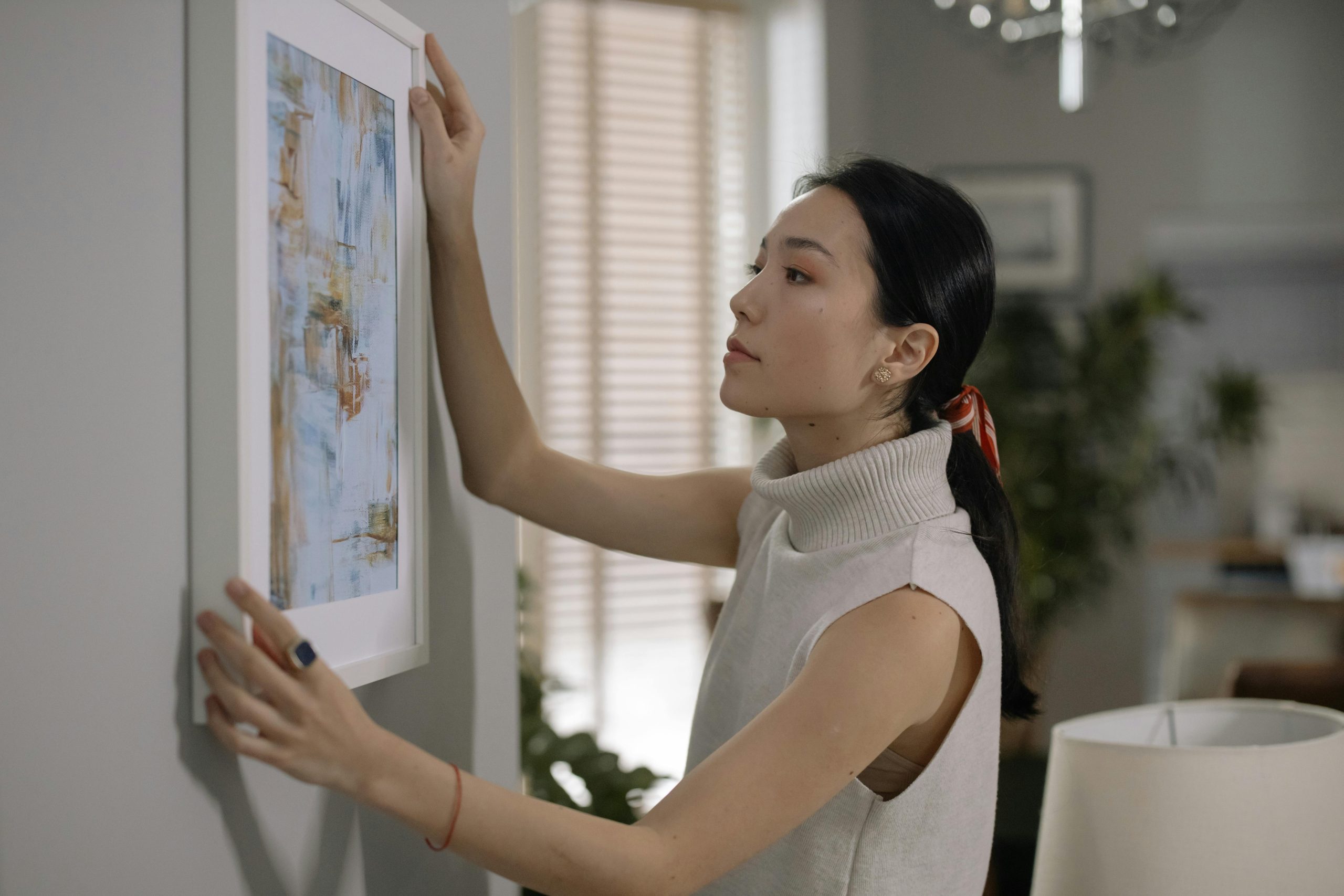 woman hanging a framed print on a wall