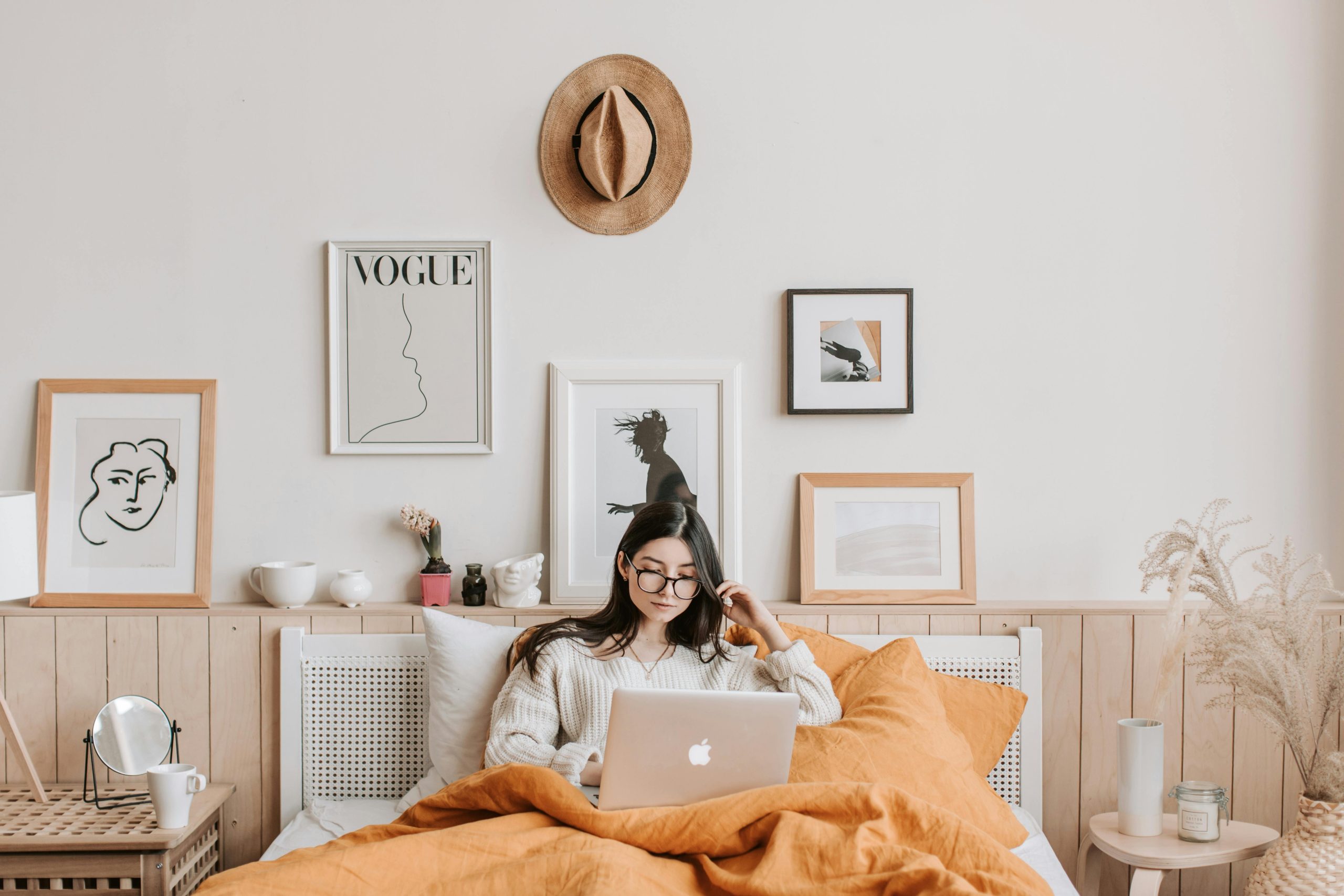 woman using a laptop in her bedroom decorated with framed prints